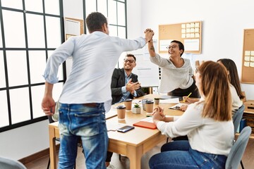 Two workers smiling happy high five during meeting at the office.