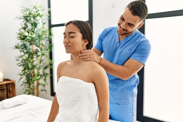 Latin man and woman wearing physiotherapy uniform having rehab session massaging neck at beauty center