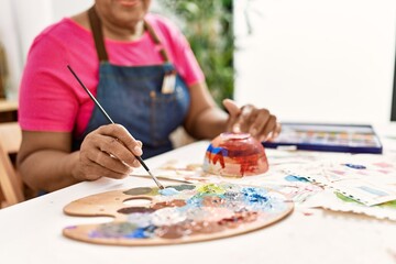 Senior african american woman painting clay ceramic at art studio