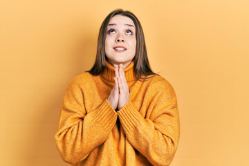 Young hispanic girl wearing casual clothes begging and praying with hands together with hope...