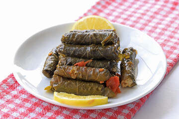 Delicious dolma (sarma) stuffed grape leaves rice, white yogurt sauce. Lebanese dolma sarma on plate. Lebanon turkish greek middle eastern cuisine. (Turkish name; Yaprak sarma)
