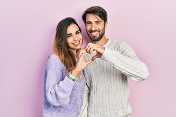 Young hispanic couple wearing casual clothes smiling in love doing heart symbol shape with hands. romantic concept.