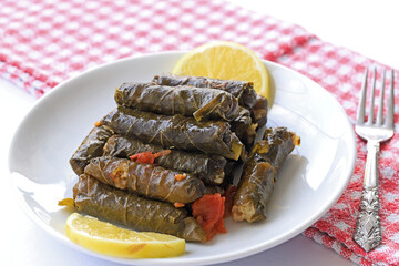 Dolma, grape leaves stuffed with rice and meat in a white plate, front view.
