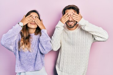 Young hispanic couple wearing casual clothes covering eyes with hands smiling cheerful and funny. blind concept.