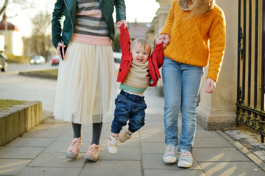 Two Big Sisters And Their Baby Brother Having Fun Outdoors. Two Young Girls Holding Their Baby Boy Sibling On Sunny Spring Day. Kids With Large Age Gap.