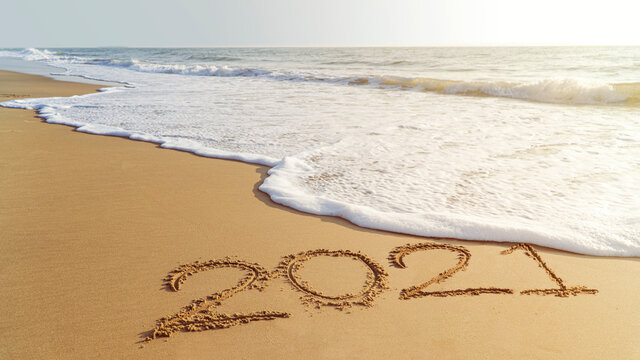 Goodbye, 2021 hello to 2022 happy New Year coming. Handwriting on the beach.