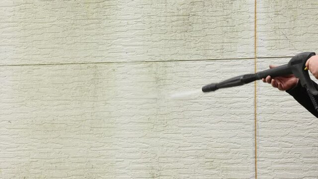 Man cleaning walls with high pressure power washer. Washing cladding walls house. High quality 4k footage