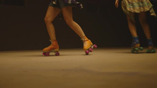 Female legs in roller blades, skating fast at the roller park on floor . Close-up legs of young women is professionally skating . Different kind of and colorful vintage roller blades . Slow Motion