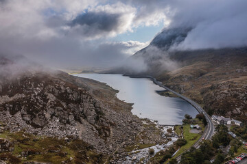 Aerial view of flying drone Epic Autumn Fall landscape image of view along Ogwen vslley in Snowdonia National Park with moody sky and mountains