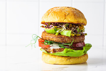 Vegan burger with avocado, tomato and nut sauce, white background.
