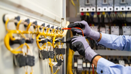 Electrical engineer using digital multi-meter measuring equipment to checking electric current...