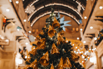 Creative Christmas tree decorated with gold Christmas toys. Festive atmosphere and shiny decorations in the interior with bokeh lights
