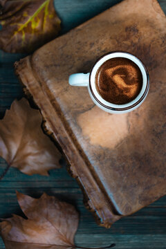 Hot coffee and book with autumn leaves on wood background. Seasonal relax concept.Selective focus.Top view..