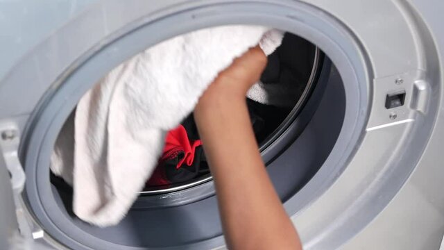 putting towel and cloths in a washing machine.