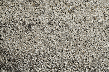 The texture of a gray cement wall interspersed with white marble chips.