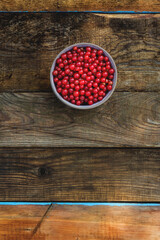 Red currants in a ceramic bowl on a wooden vintage background.