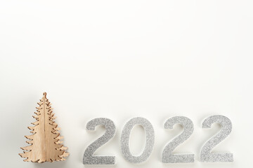 Little wooden Christmas tree with 2022 numbers on light background. Copy space.