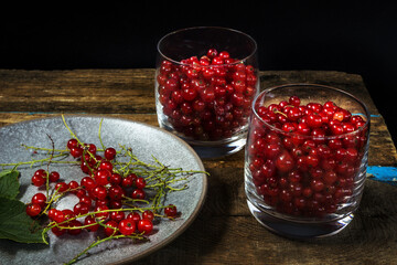 Red currants in a glass goblet on a black background.