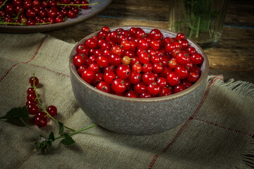 Red currants in a bowl on a black background. Berries from the village garden. Wooden vintage table