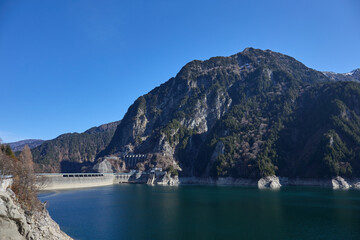 Fototapeta na wymiar 秋（11月） カンパ谷の吊り橋付近から見た黒部ダム 富山県