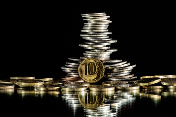 Coins of different denominations are stacked haphazardly on a black background. Concept-increase in taxes, income. Copy space.