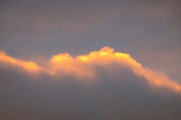 Sunlit clouds against a grey sky. The leaden colour of the sky. Heavy clouds. Late autumn.