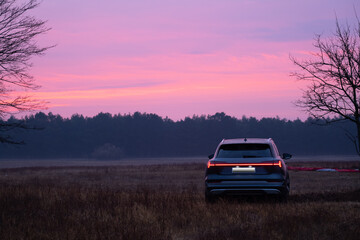 Close-up of a car on a purple background of sunset and forest, copy space