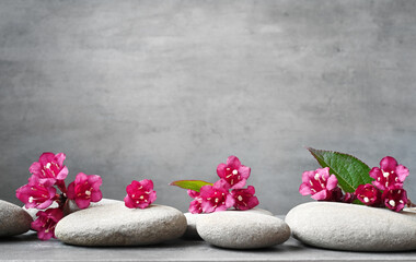 Spa stones with green leaf and flowers on grey background.