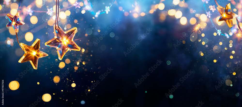 Wall mural christmas stars lights - golden string hanging in blue background with abstract defocused bokeh