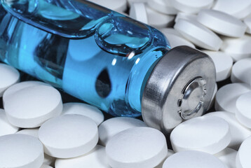 Medical bottle with blue vaccine surrounded by white pills