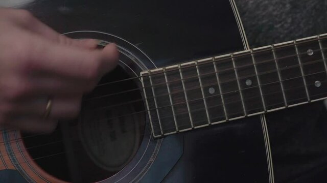 Close up, white person strumming their acoustic guitar in an upbeat fashion. A quick paced song.