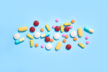 Assorted multicolored medicine pills, capsules and tablets on blue background with copyspace for your text. Immune system vitamins and supplemets. Dietary bio supplements