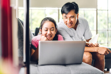 Father and asian kid little girl learning and looking at laptop computer making homework studying knowledge with online education e-learning system.children video conference with teacher tutor