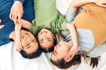 Top view of portrait enjoy happy smiling love asian family father and mother with young parent little cute asian girl looking at camera in moments good time lying on the floor at home