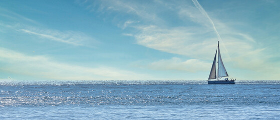 Small sailboat sailing through a silver sea in a sunny day 