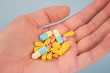 Man's hand holding assorted multicolored medicine pills, capsules and tablets. A handful of pills. Immune system vitamins and supplemets. Dietary bio supplements