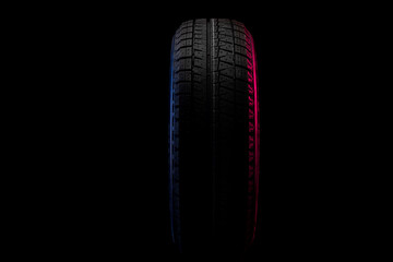 tire with winter tread in profile on black background with blue red light