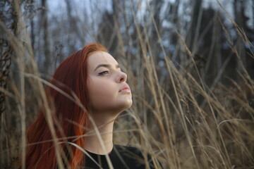 Closeup portrait of a beautiful young girl in the forest beauty cute pretty face female smile lady woman fun red hair