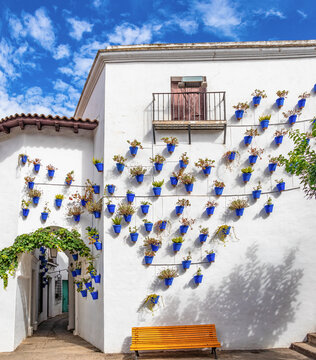 Andalusian neighborhood with blue flower pots hanging on the white walls of Arcos de la frontera, in Poble Espanyol, Spanish Village in Barcelona, Catalonia, Spain.