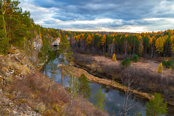Autumn nature with a river of pines and rocks, yellow foliage against the background of the evening sky. Russia National Park