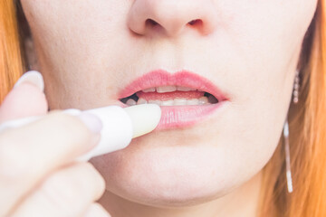 young caucasian woman with lip balm close up