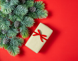 Christmas card with fir branches pine cones gift box with red ribbon on gray concrete background.