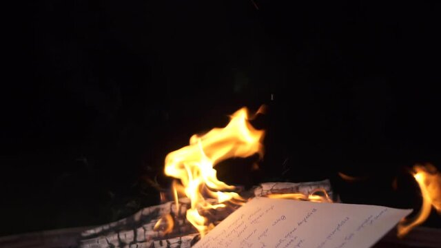 burn in fire handwritten letter. hand throws printed document. Throw piece of paper into fire. burn memories and evidence. cleanse land and preserve environment. destroy paper in camp fire and taxes