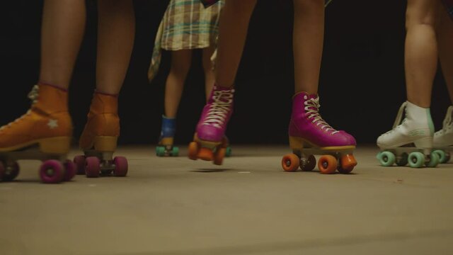 Female legs in roller blades, skating fast at the roller park on floor . Close-up legs of young women is professionally skating . Different kind of and colorful vintage roller blades . Slow Motion