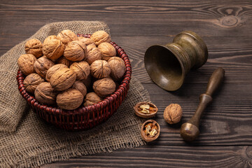 walnuts in a basket and bronze.mortar on a wooden table