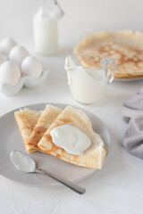 Thin pancakes with sour cream. White background. Nice breakfast. Pancake ingredients.