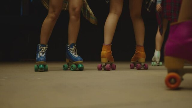 Female legs in roller blades, skating fast at the roller park on floor . Close-up legs of young women is professionally skating . Different kind of and colorful vintage roller blades . Slow Motion