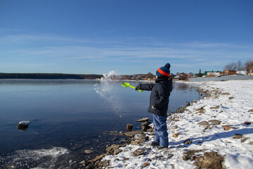 a boy in winter on the lake shore