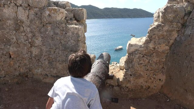 Kalekoy, Simena, Turkey - 17th of October 2021: 4K Boy plays on the ancient canon at the medieval castle
