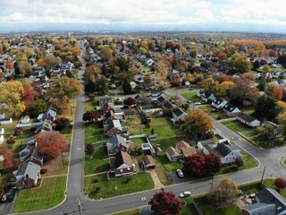 The aerial view of the residential neighborhood surrounded by stunning colors of fall foliage near...